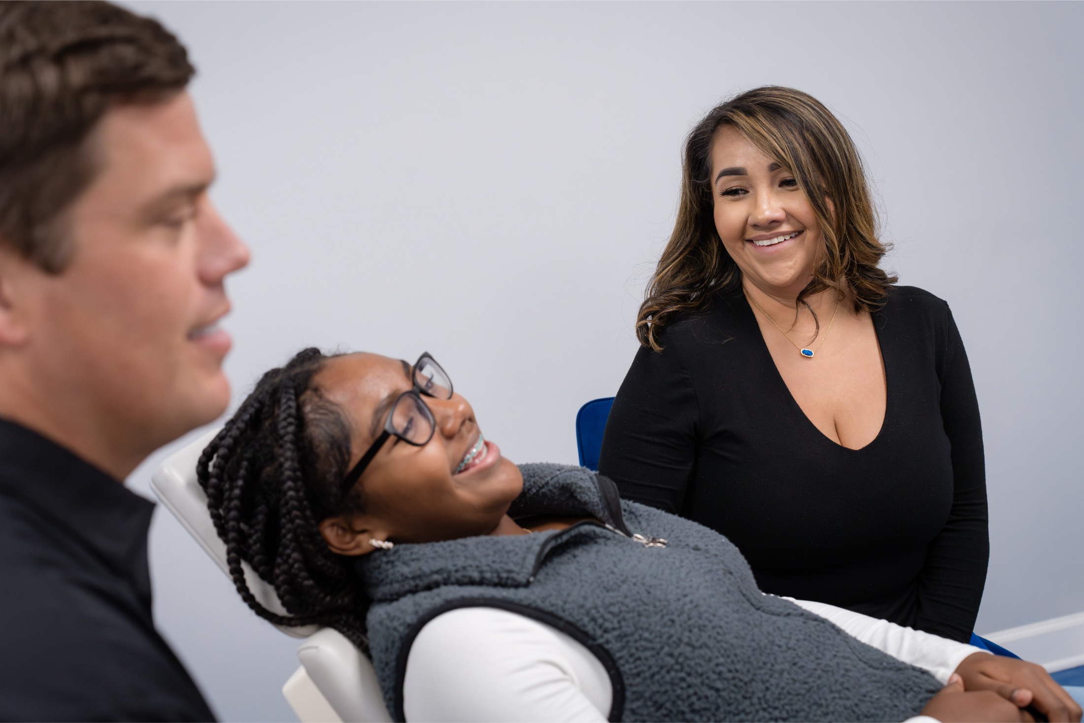 Patient consultation with Midway Orthodontics staff, smiling orthodontist and patient in exam chair.